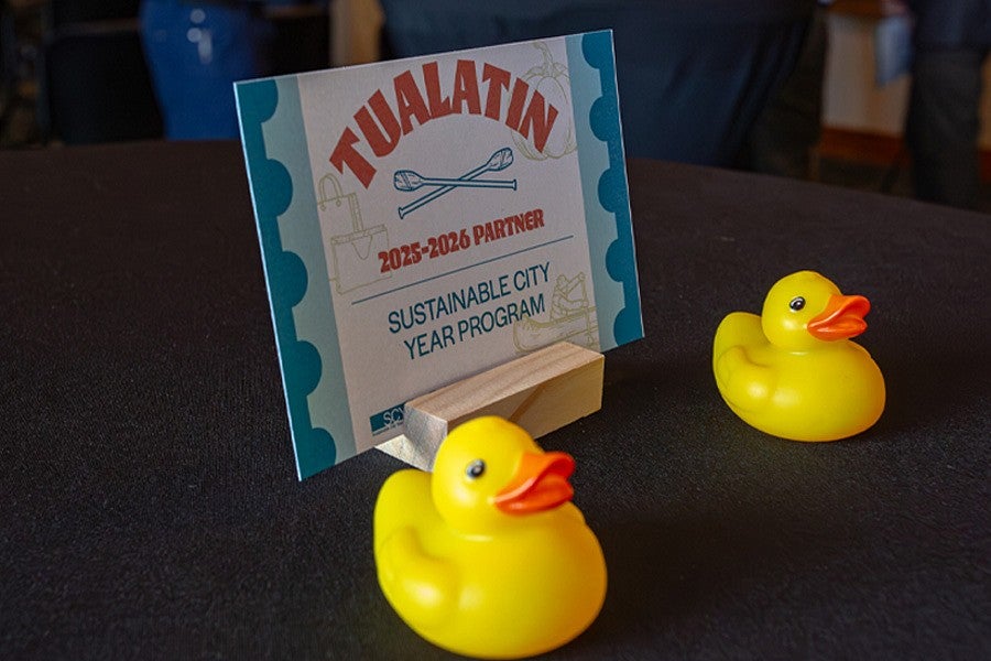 Photograph of Tualatin kick off. Shows a close up of a designed card with the city name and the Sustainable City Year Program name with two toy ducks in front.