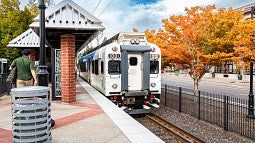 Photograph of an electric train leaving an outdoor train station. 