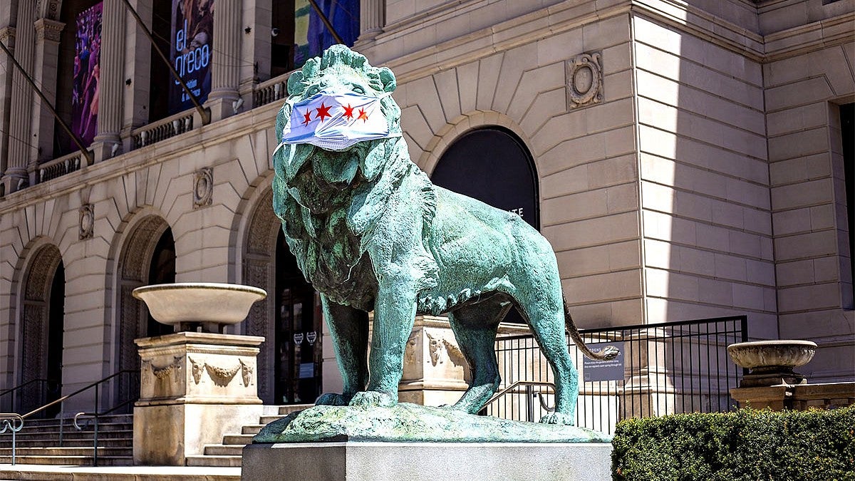 Photo of the exterior of a Chicago museum and lion statue with a mask